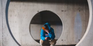 5 Reasons to Build A Safe Room Or Storm Cover man with smartphone sitting in round passage