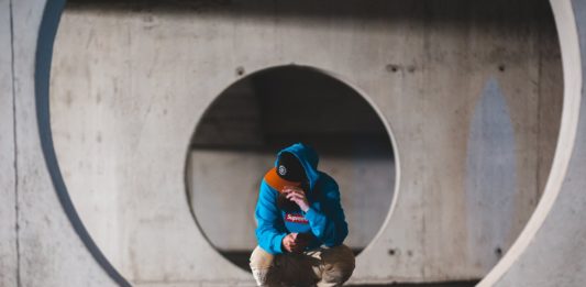 5 Reasons to Build A Safe Room Or Storm Cover man with smartphone sitting in round passage