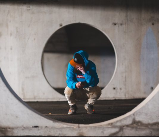 5 Reasons to Build A Safe Room Or Storm Cover man with smartphone sitting in round passage