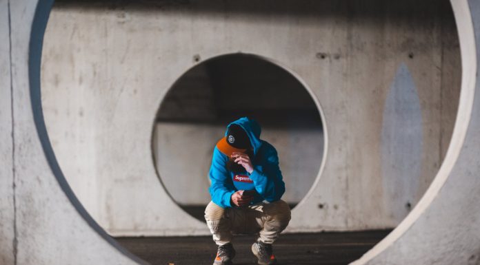 5 Reasons to Build A Safe Room Or Storm Cover man with smartphone sitting in round passage