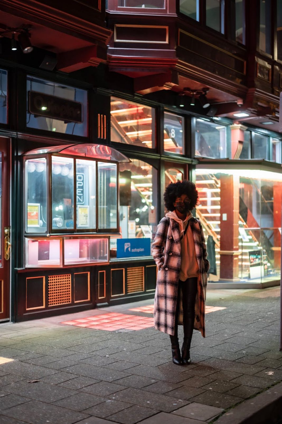 stylish black woman in checkered coat on urban pavement