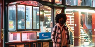 Lockdowns May Prevent The Virus From Naturally Weakening stylish black woman in checkered coat on urban pavement