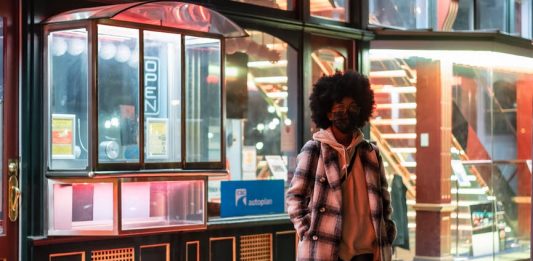 Lockdowns May Prevent The Virus From Naturally Weakening stylish black woman in checkered coat on urban pavement